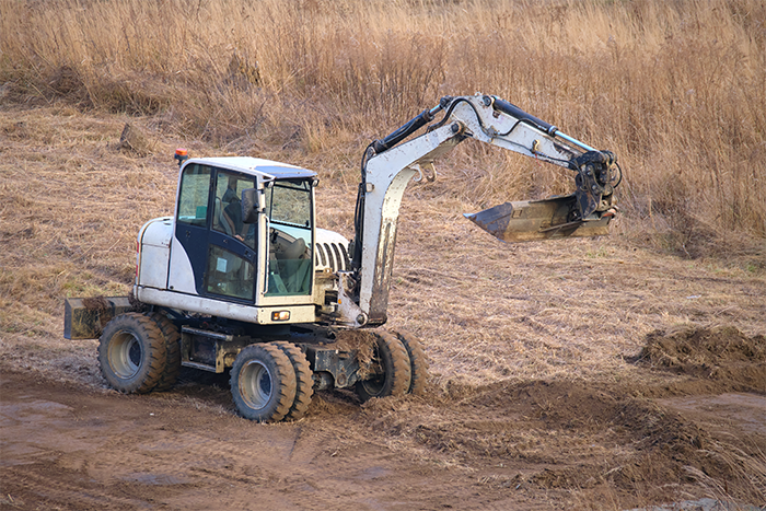 Photo of a white digger in a muddy field.