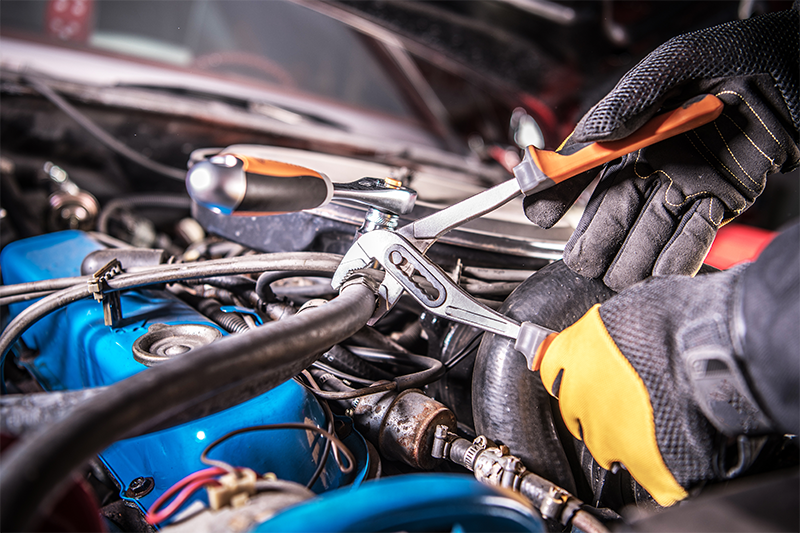Close up photo showing a mechanic's hands fixing an engine.