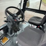Interior of a Swingo 200 sweeper, showing the two seats, the footwell and the steering wheel and pedals.
